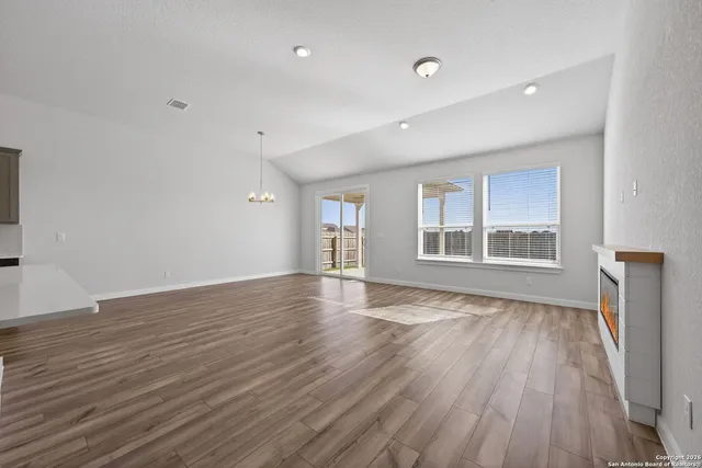a view of an empty room with wooden floor and window