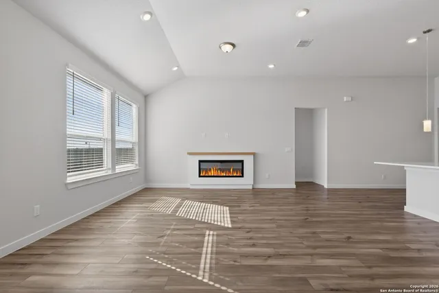 a view of an empty room with a window and wooden floor
