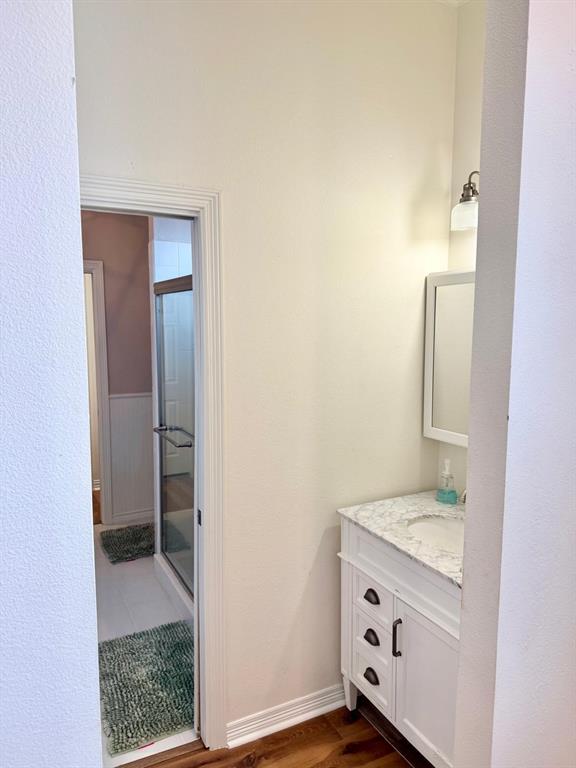 2300 Berend Road Pilot Point, TX 76258 - Photo 11 of 39 Bathroom featuring vanity, a stall shower, dark wood-type flooring, and a textured wall