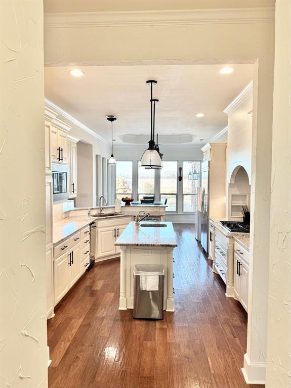 2300 Berend Road Pilot Point, TX 76258 - Photo 2 of 39 Kitchen featuring a textured wall, dark wood-type flooring, hanging light fixtures, a peninsula, and a kitchen island with sink