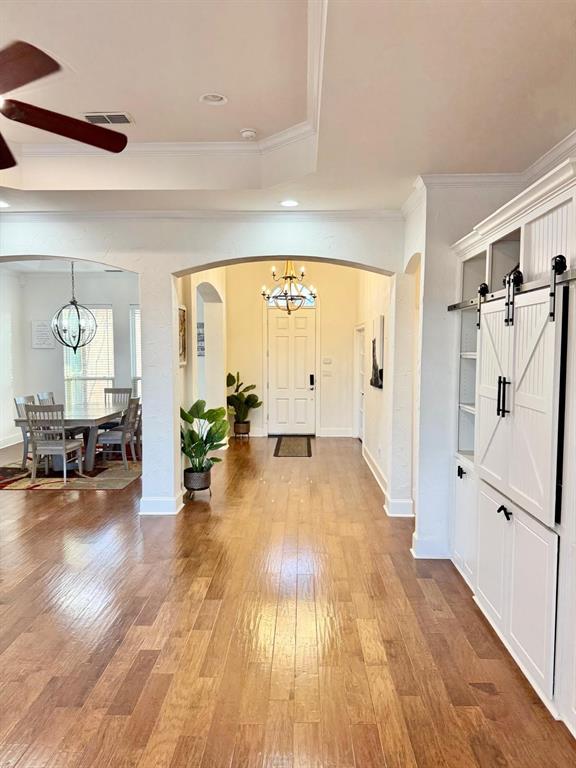 2300 Berend Road Pilot Point, TX 76258 - Photo 33 of 39 Entrance foyer with hanging lights, a barn door, light wood-style floors, arched walkways, and ornamental molding