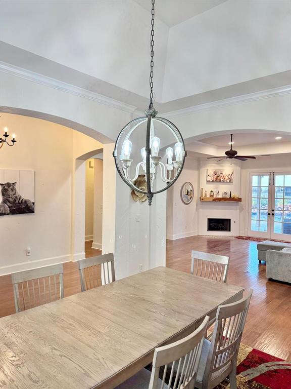 2300 Berend Road Pilot Point, TX 76258 - Photo 4 of 39 Dining area featuring a chandelier, arched walkways, hardwood / wood-style floors, a fireplace, and a high ceiling