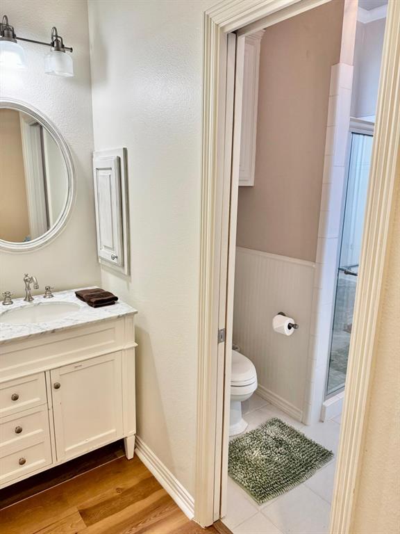 2300 Berend Road Pilot Point, TX 76258 - Photo 6 of 39 Full bath with vanity, a shower stall, a wainscoted wall, and light wood-style flooring