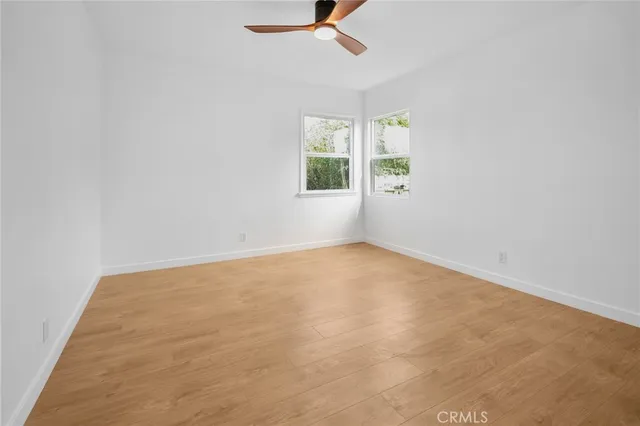 an empty room with windows and ceiling fan view