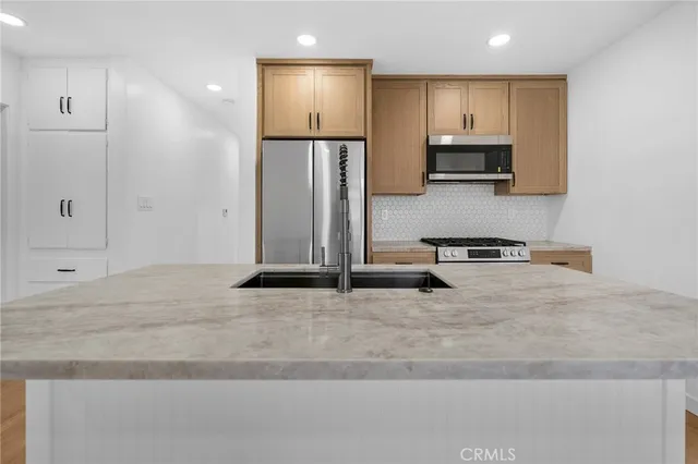 a view of kitchen with stainless steel appliances refrigerator stove microwave and cabinets