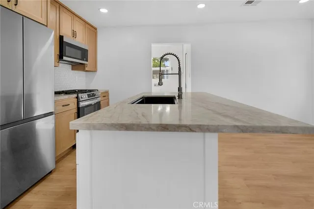 a kitchen with stainless steel appliances granite countertop a refrigerator a stove and a sink with wooden floor