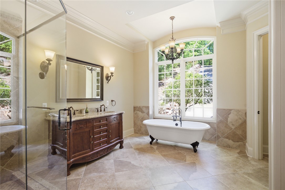 130 River Ridge Road Sunset, SC 29685 - Photo 16 of 47 This primary bathroom presents a grand window, a classic clawfoot tub, and a vanity with dual sinks.
