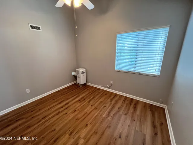an empty room with wooden floor and windows