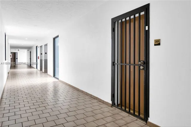 a view of a hallway with wooden floor and a bathroom