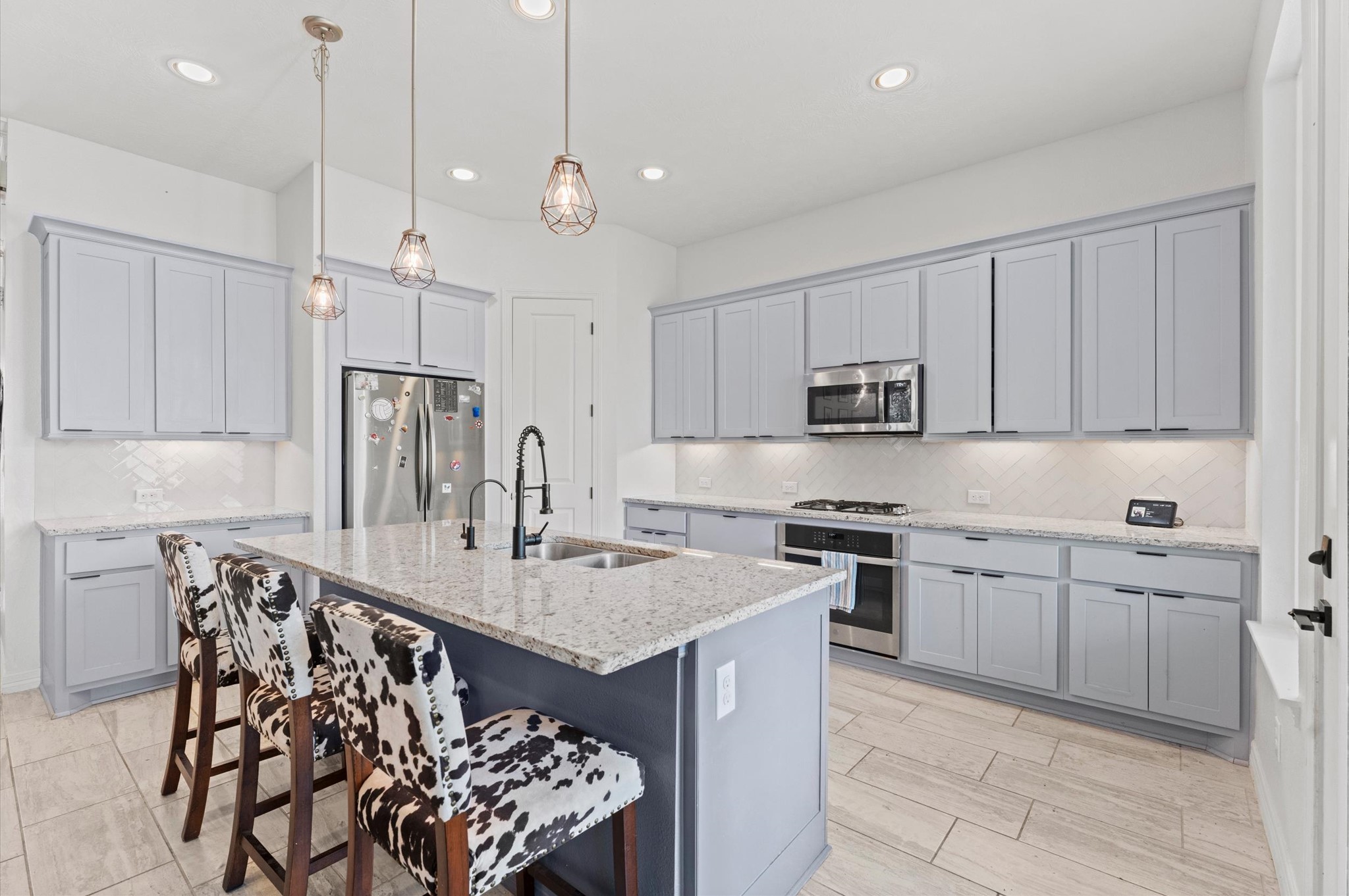 3510 Whitman Drive Rosharon, TX 77583 - Photo 2 of 25 This modern kitchen features sleek gray cabinetry, stainless steel appliances, and a spacious island with a granite countertop.