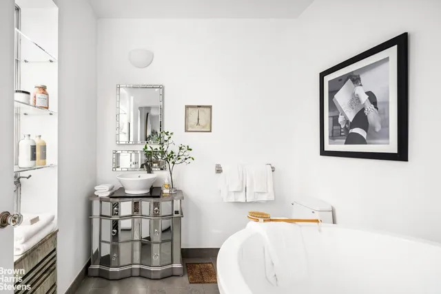 a bedroom with a bed a mirror and a large window with outer view