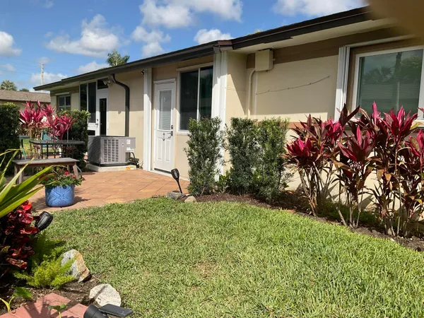 a couple of flower plants in front of yellow house