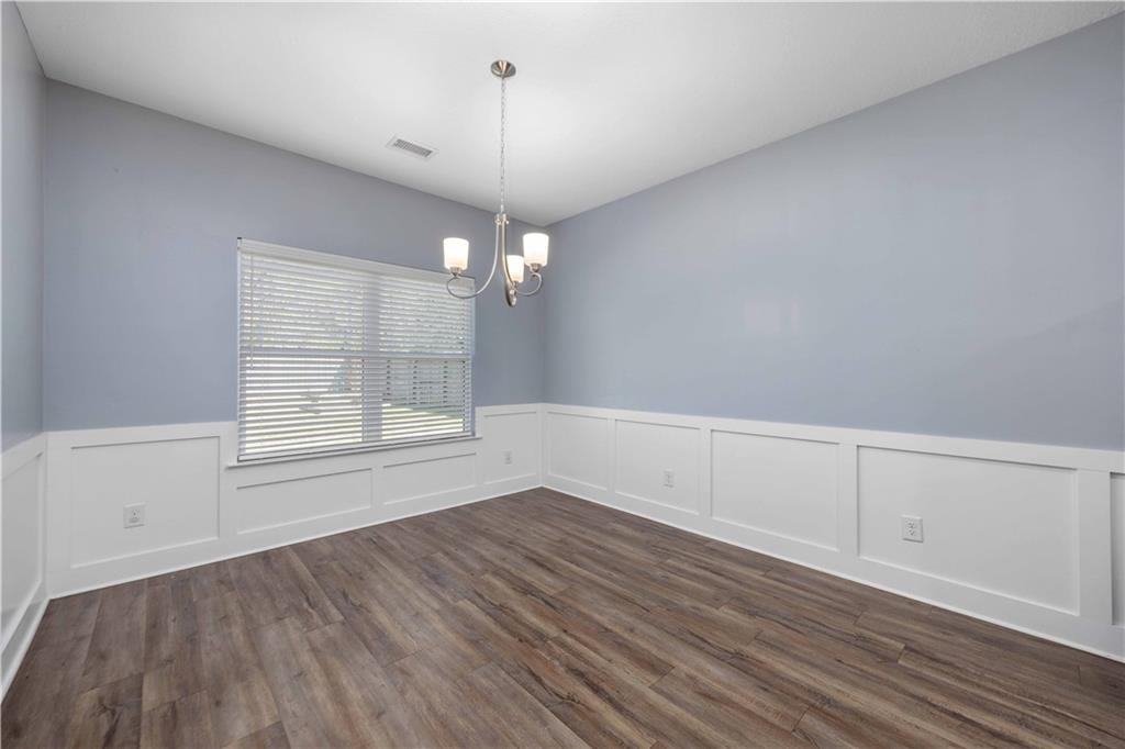 70 Apache Trail Fort Mitchell, AL 36856 - Photo 18 of 33 Unfurnished room with wainscoting, hanging lights, dark wood-style floors, and a decorative wall