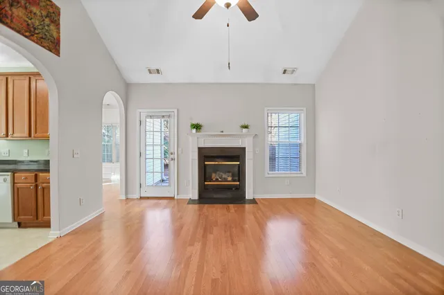 an empty room with windows fireplace and a kitchen view