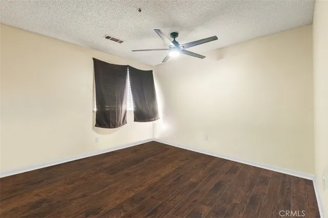an empty room with wooden floor fan and windows