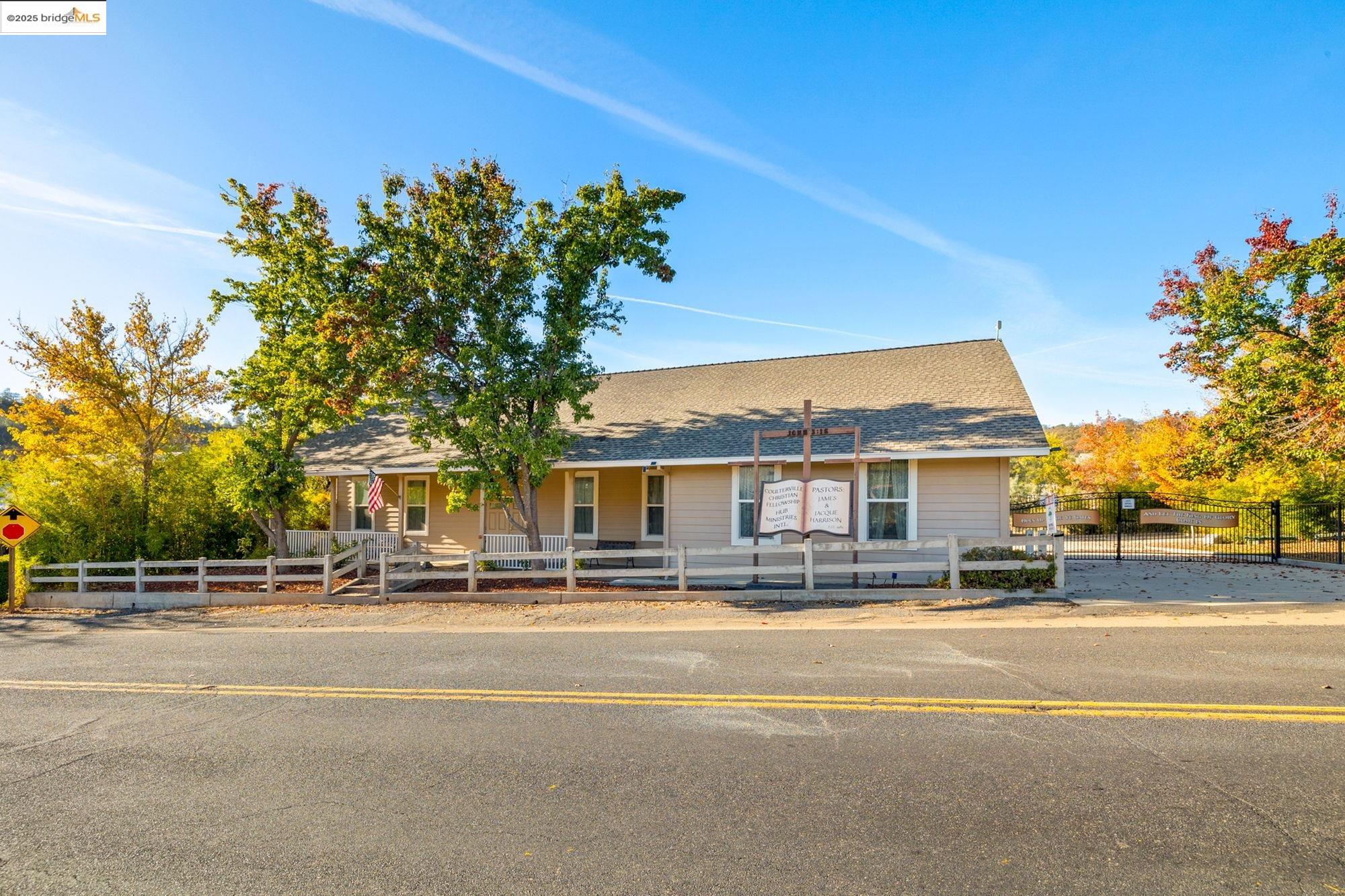 5033 Main Street Coulterville, CA 95311 - Photo 2 of 38 View of front of property featuring a fenced front yard, roof with shingles, and covered porch