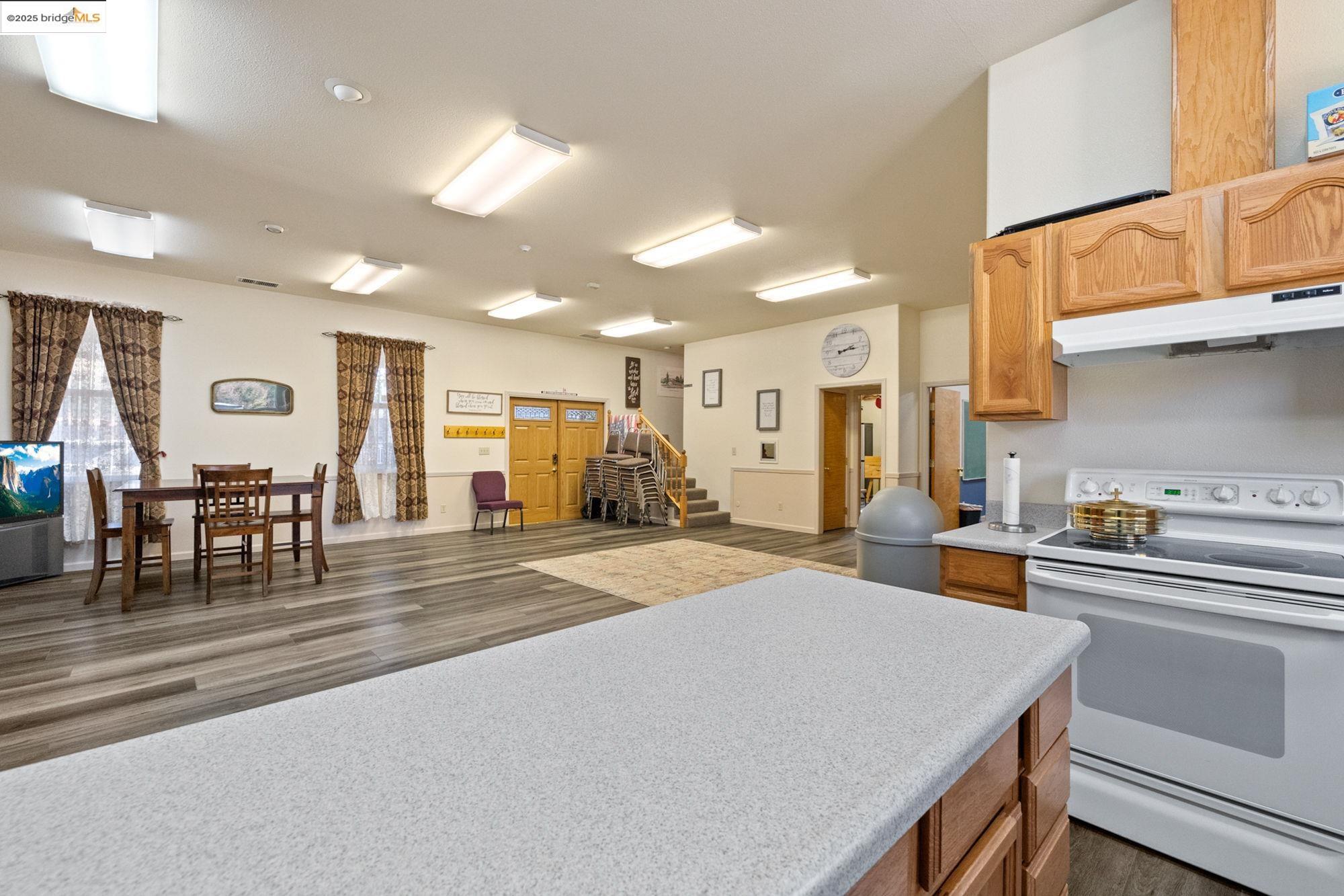 5033 Main Street Coulterville, CA 95311 - Photo 38 of 38 Kitchen featuring white electric stove, open floor plan, light countertops, under cabinet range hood, and dark wood finished floors