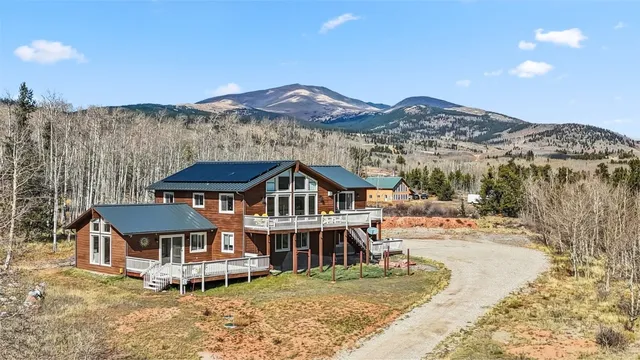 a front view of a house with a yard and mountain view in back