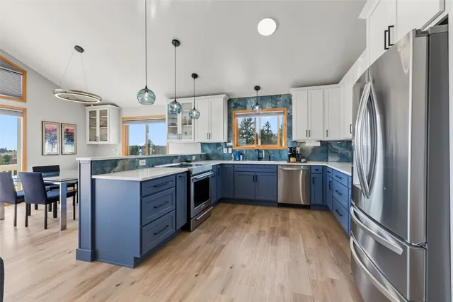 a kitchen with stainless steel appliances a sink a window a wooden floor and a window