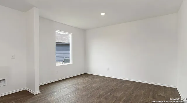 an empty room with wooden floor and window