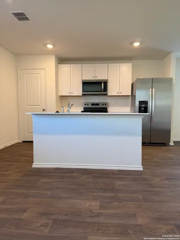 a large kitchen with stainless steel appliances a large counter top a stove and a refrigerator