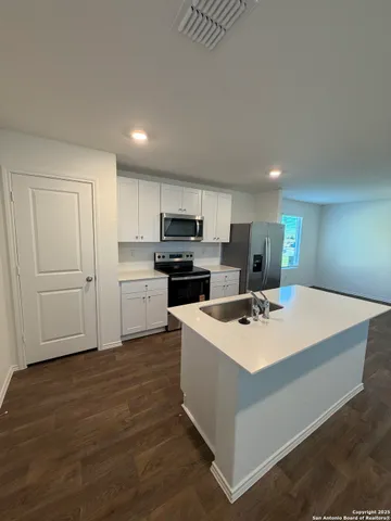 a kitchen with kitchen island a white counter top space cabinets and stainless steel appliances