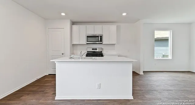a kitchen with granite countertop a sink cabinets and a wooden floor