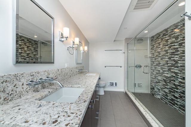 a bathroom with a granite countertop sink a toilet and shower