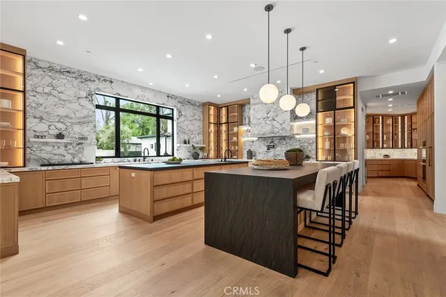 a kitchen with stainless steel appliances granite countertop a stove a sink dishwasher and a large refrigerator with wooden floor