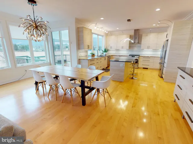 a dining hall with stainless steel appliances a dining table chairs and a chandelier