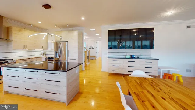 a large kitchen with stainless steel appliances a large counter top and a view of living room