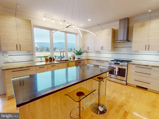 a kitchen with stainless steel appliances granite countertop a sink a stove and a wooden floors
