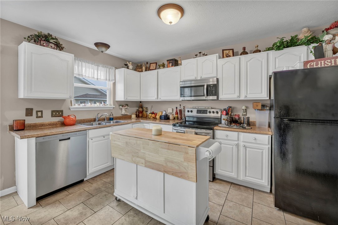 3887 Reeves Lane Medina, OH 44256 - Photo 18 of 42 Kitchen featuring sink, stainless steel appliances, light tile patterned floors, a kitchen island, and white cabinets