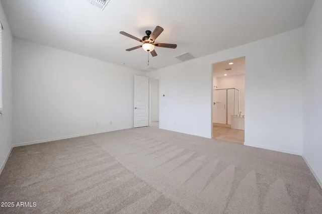 a view of an empty room and chandelier fan