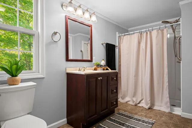 a bathroom with a sink a mirror a toilet and a window