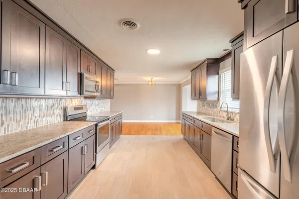 a large kitchen with stainless steel appliances granite countertop a refrigerator and a sink