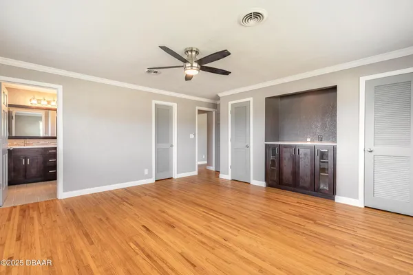 a view of empty room with wooden floor and ceiling fan
