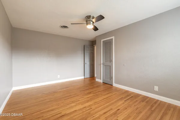 a view of a room with wooden floor and ceiling fan