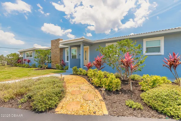 a front view of a house with a yard and fountain in middle of the road