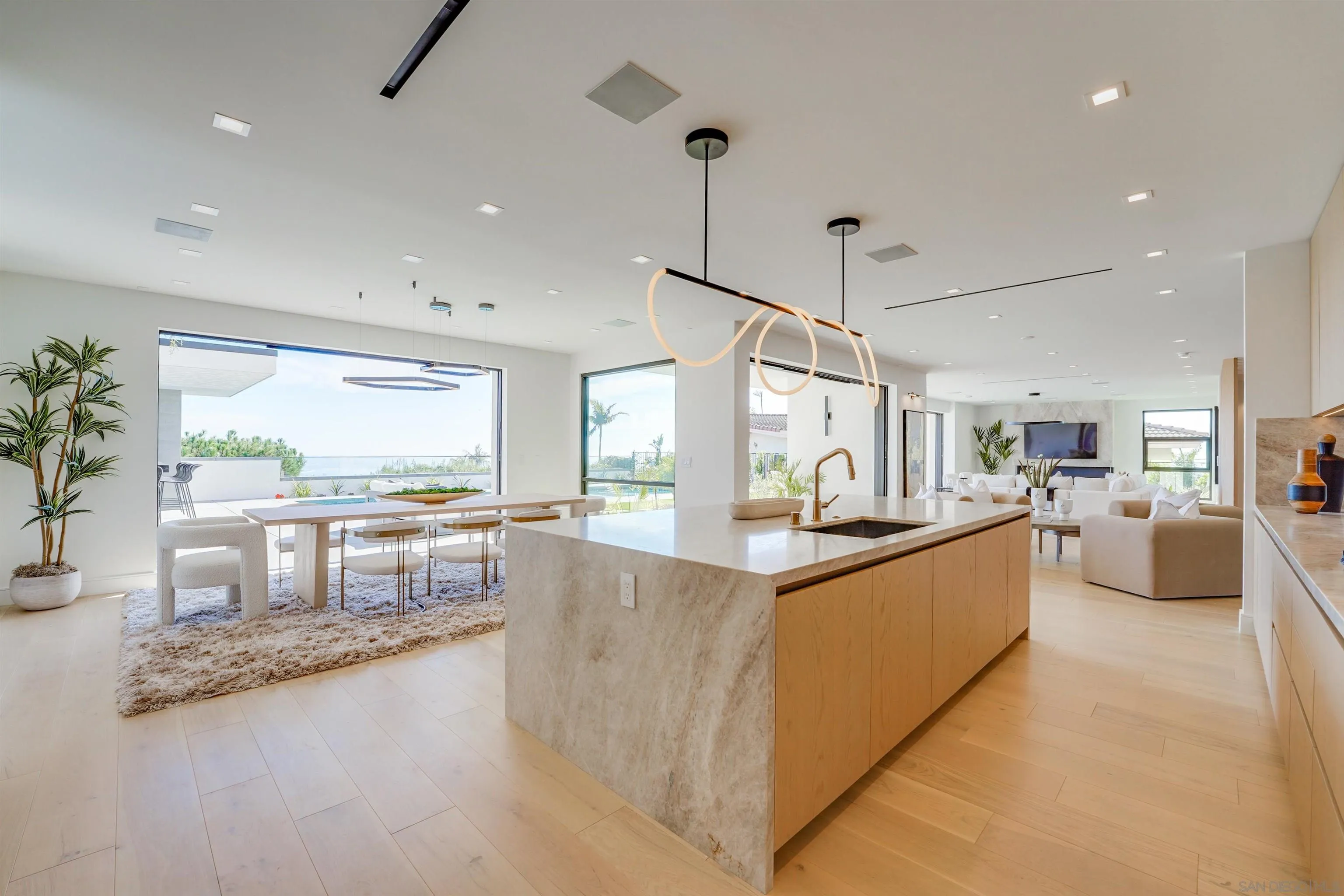 1205 La Jolla Rancho Road La Jolla, CA 92037 - Photo 25 of 75 a large kitchen with kitchen island a large counter top a stove a sink a dining table and chairs with wooden floor