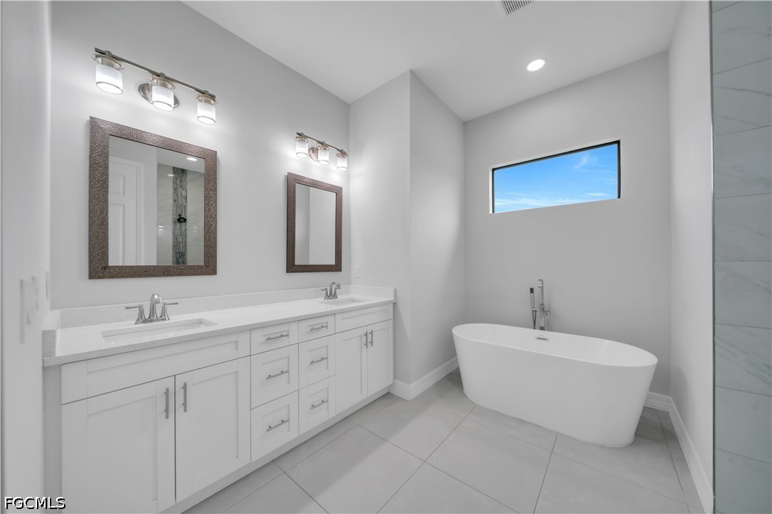 3509 38th Street Southwest Lehigh Acres, FL 33976 - Photo 21 of 47 a spacious bathroom with a double vanity sink mirror and bathtub