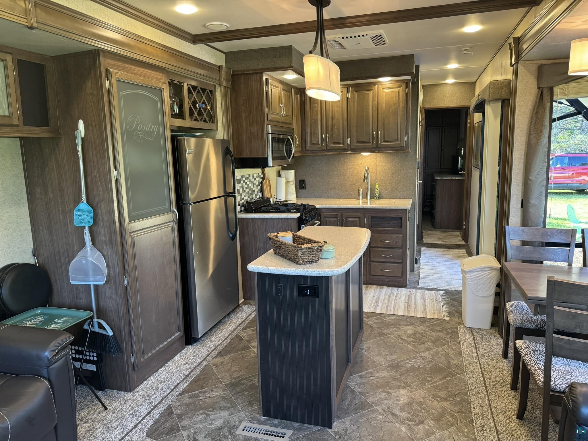 840 Stanley Road Two Harbors, MN 55616 - Photo 4 of 14 Kitchen with decorative light fixtures, appliances with stainless steel finishes, a center island, ornamental molding, and dark brown cabinetry