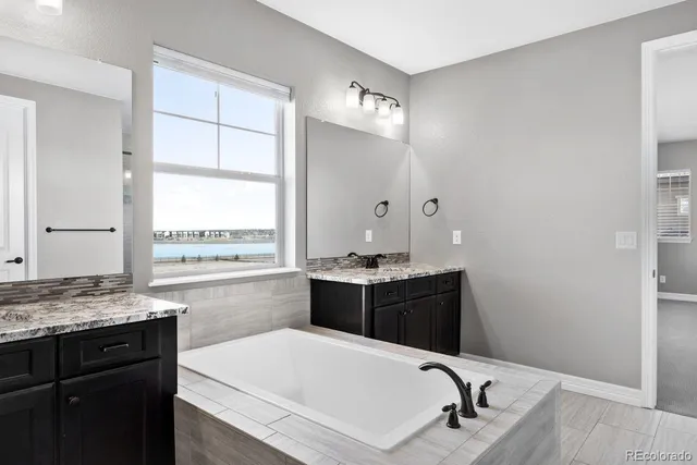 a bathroom with a granite countertop sink tub and mirror