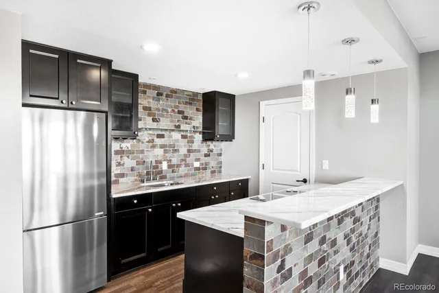 a kitchen with stainless steel appliances kitchen island granite countertop a refrigerator and a sink