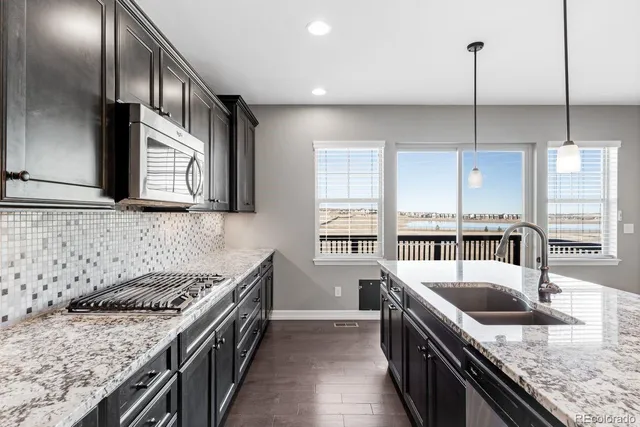 a kitchen with stainless steel appliances granite countertop a sink a stove and a refrigerator