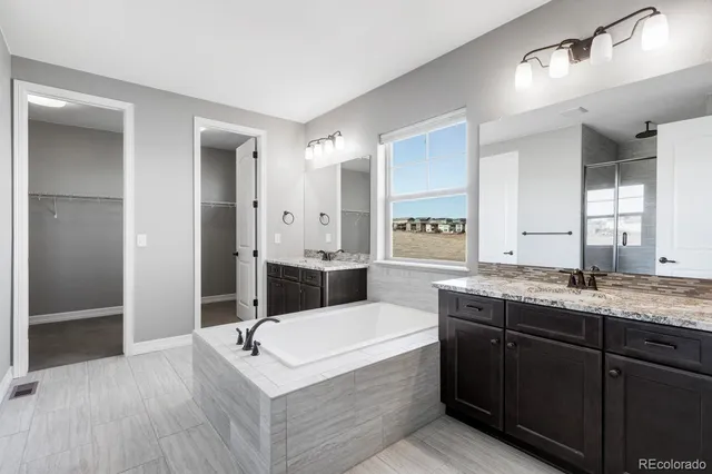 a spacious bathroom with a granite countertop sink mirror and bathtub