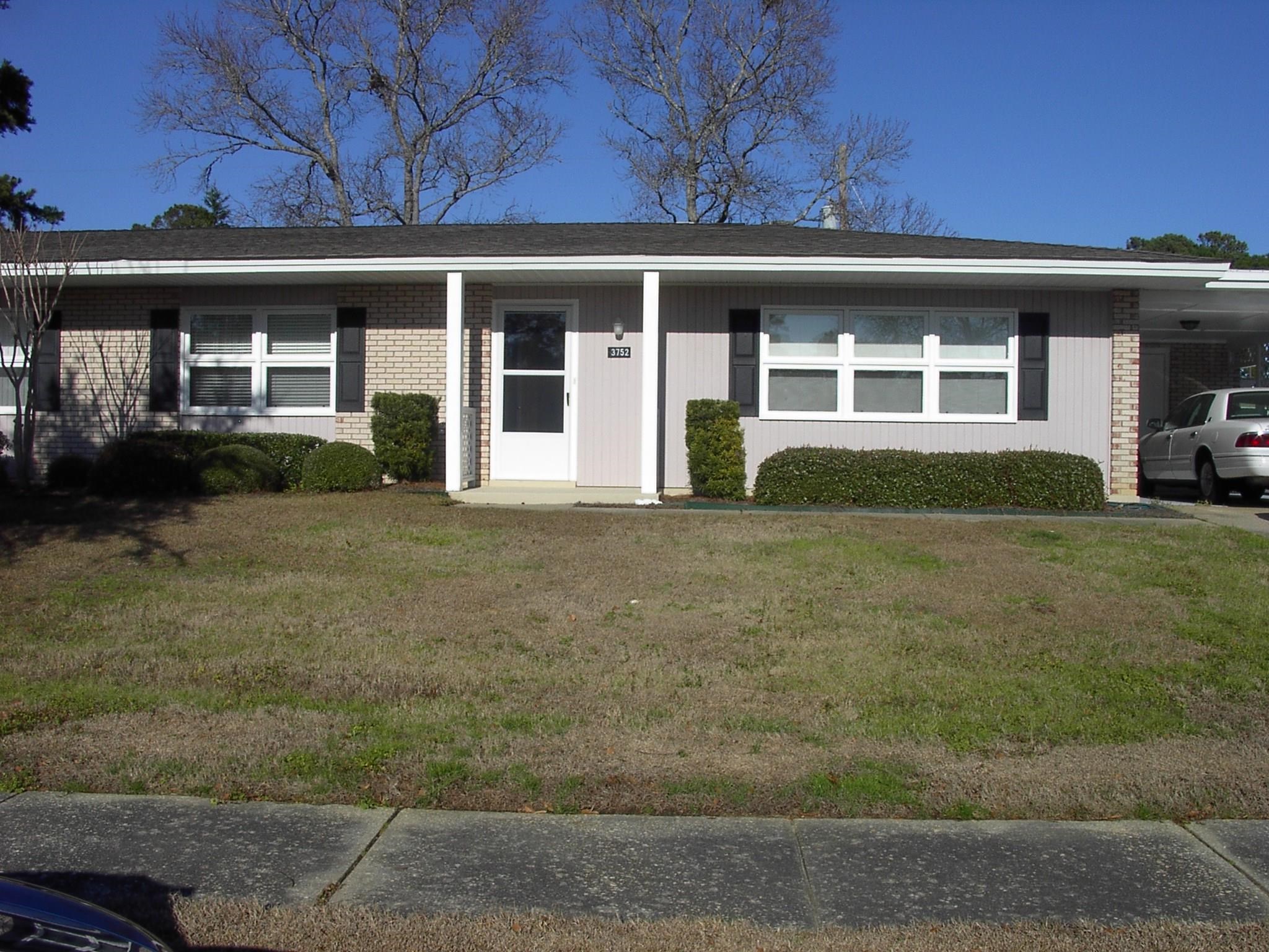 Ranch-style house featuring an attached carport, a front yard, a porch, and brick siding