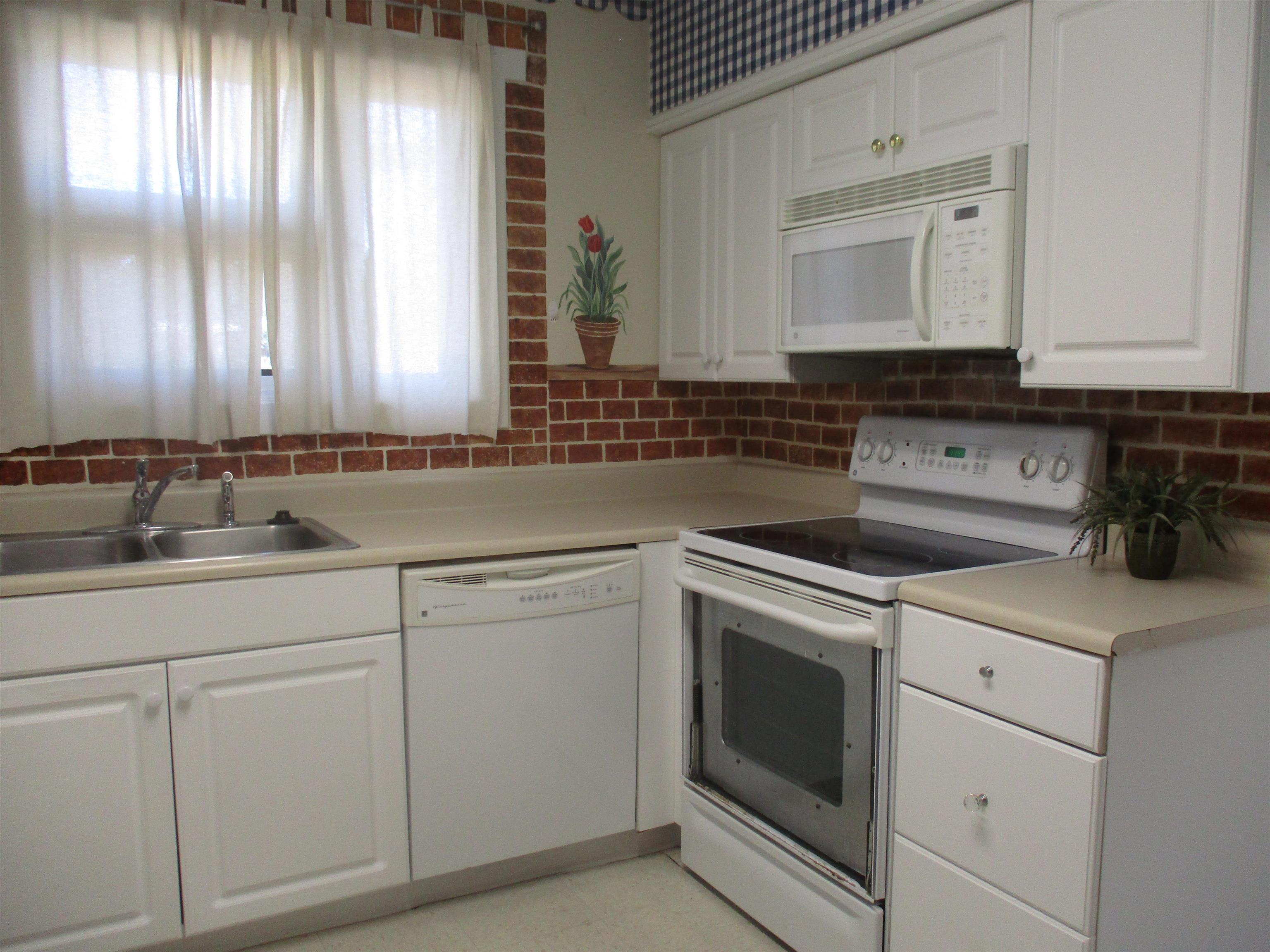 3752 Tea Rose Street, Unit 3752 Myrtle Beach, SC 29577 - Photo 4 of 8 Kitchen with white appliances, white cabinetry, light countertops, and backsplash
