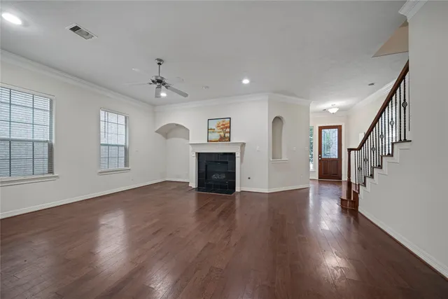an empty room with wooden floor fireplace and windows