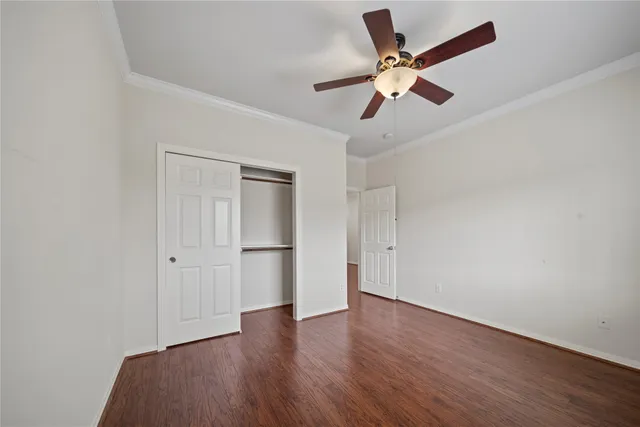 an empty room with wooden floor ceiling fan and window